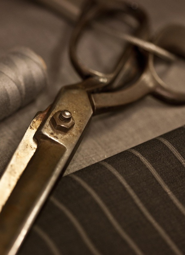 Antique tailor's shears and a thread spool on pinstripe suiting